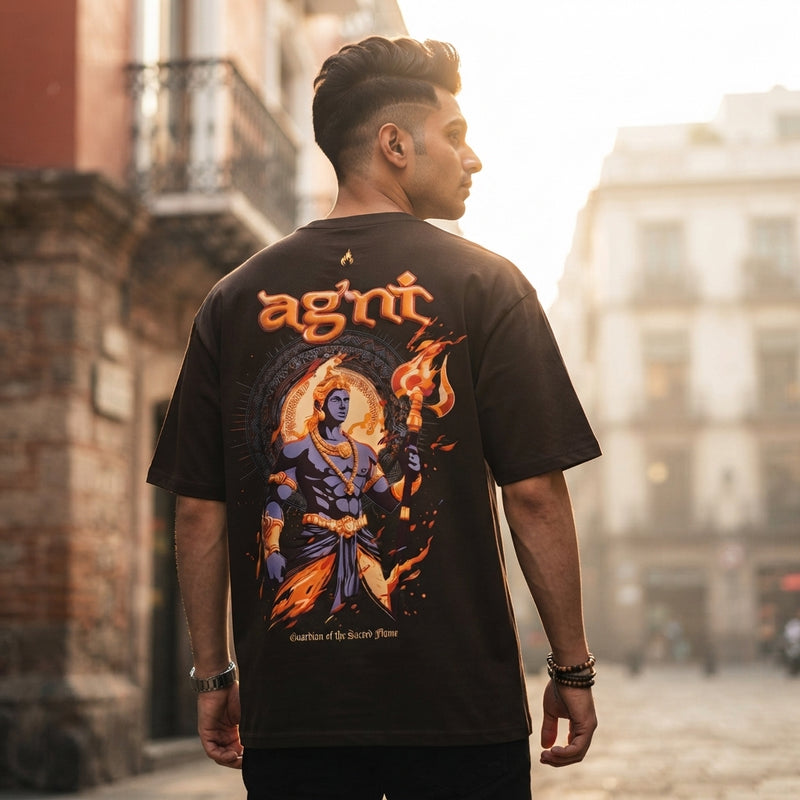 South Asian man wearing an Agni oversized puff print T-shirt standing on a city street during golden hour.